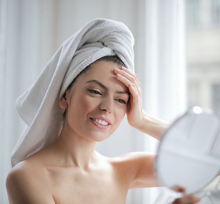 Woman with a towel on her head smiling in the mirror